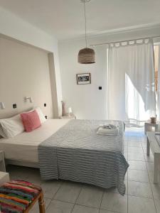 a white bedroom with a bed and a window at Heras Garden in Vasiliki