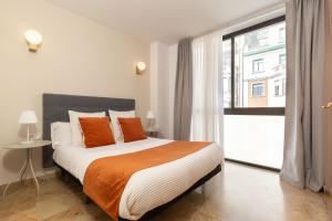 a bedroom with a bed with orange pillows and a window at Picasso Suites in Barcelona