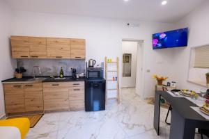 a kitchen with wooden cabinets and a black refrigerator at Kyma Apartment - Giardini Naxos in Giardini Naxos