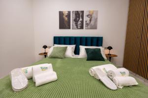 a bedroom with a green bed with towels on it at Kyma Apartment - Giardini Naxos in Giardini Naxos