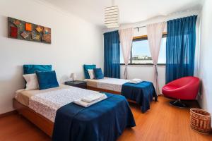 a bedroom with two beds and a red chair at Santa Maria Apartamentos in Tavira +67 photos