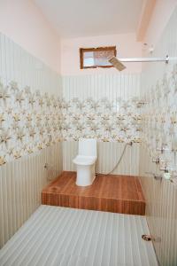 a white bathroom with a toilet and a shower at Hotel Saraswati in Nautanwa