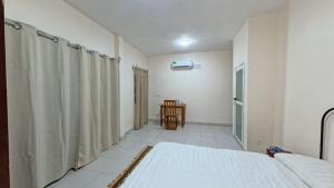 a white room with a bed and a table at Captain Purunchi in Cotonou