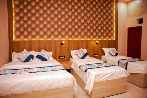 a bedroom with two beds with white sheets and blue pillows at Hotel Saraswati in Nautanwa