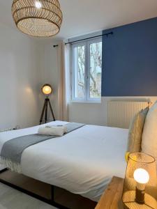 a bedroom with a large white bed and a window at Jasmin in Bourg-lès-Valence