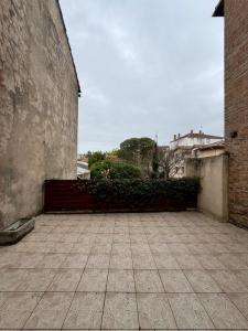 an empty courtyard with a brick wall and bushes at Jasmin in Bourg-lès-Valence