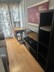 a living room with a table and a tv at Bright double studio with large patio space in Raynes Park