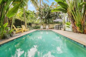 a swimming pool with chairs and palm trees at Cottage 3 on Penn - Pool in West Palm Beach