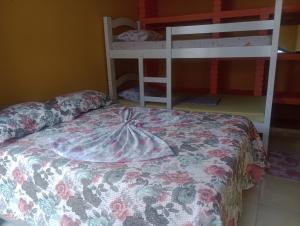 a bedroom with a bed with a flowered blanket and bunk beds at Recanto do MIMI in Bertioga