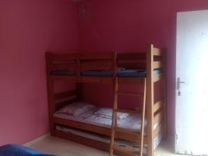 two bunk beds in a room with a red wall at Recanto do MIMI in Bertioga