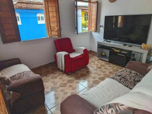 a living room with a tv and a red chair at Belvedere das Estrelas in Lençóis