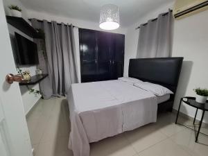 a bedroom with a white bed with a black headboard at Hermoso Loft in Santo Domingo