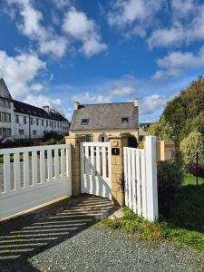 a white fence in front of a house at Ti Ar Skol, chambre d'hôtes in Huelgoat