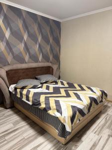 a bedroom with a bed with a comforter and two pillows at Апартамент студия in Khmelnytskyi