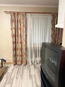 a living room with a tv and a curtain at Апартамент студия in Khmelnytskyi