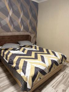 a bedroom with a bed with a black and yellow comforter at Апартамент студия in Khmelnytskyi +4 photos