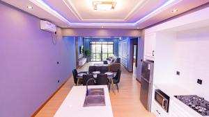 a kitchen and living room with purple walls and a table and chairs at K&K Luxurious Landing in Limbe