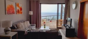 a living room with a couch and a tv and a balcony at First Balcony - Porto Santo in Porto Santo