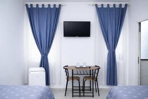 a bedroom with blue curtains and a table with chairs at Hotel Road Rooms in Voluntari