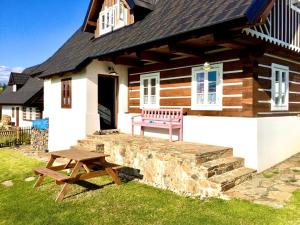 a wooden house with a bench and a picnic table at Chalupa U Pastýře in Vysoké nad Jizerou
