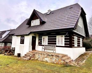 a black and white house with a bench in front of it at Chalupa U Pastýře in Vysoké nad Jizerou