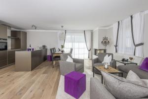 a living room with purple furniture and a kitchen at Hotelino Petit Chalet in Celerina