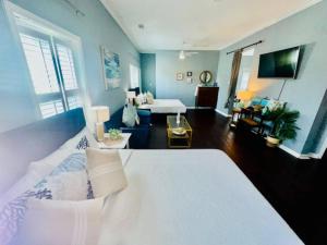 a bedroom with a white bed and a living room at Surf & Strand Unit B in Galveston