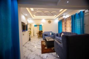 a living room with blue couches and a television at Winners Home in Kumasi +13 photos