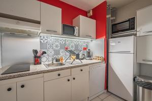 a kitchen with white cabinets and a red wall at L'escale in Angers +26 photos
