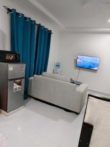 a living room with a couch and a flat screen tv at Diani Beach Studio with Pool, Beach Access in Diani Beach