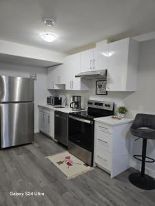 a kitchen with white cabinets and stainless steel appliances at Omos Home in Saskatoon