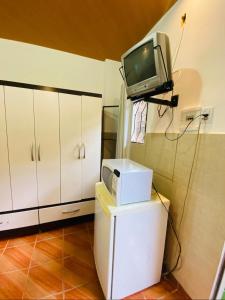 a television on top of a refrigerator in a kitchen at Microcasas in Nova Friburgo +15 photos