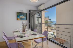 a dining room with a table and purple chairs at Apartments Glusac in Podgora