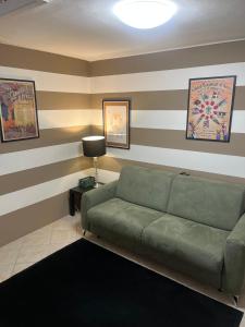 a living room with a green couch and striped walls at Eporedia Inn in Ivrea