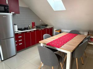 une cuisine avec des placards rouges et une table en bois avec des chaises dans l'établissement Orzechowa Zagroda, à Nowa Słupia