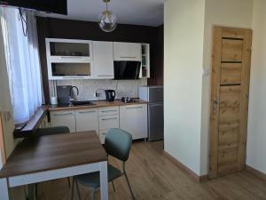 a kitchen with white cabinets and a table and chairs at Apatrament Jagielońska in Legnica +11 photos