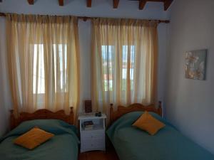 two beds in a bedroom with two windows at Giannis' House in Polichnítos