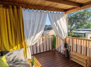 a porch with a bed and curtains on a deck at Mobile Home Annika Mar in Selce
