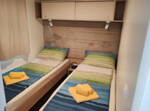 two beds in a small room with towels on them at Mobile Home Annika Mar in Selce