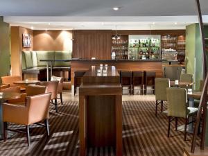 a restaurant with tables and chairs and a bar at Sunday Hotel Saarbrücken Süd in Saarbrücken