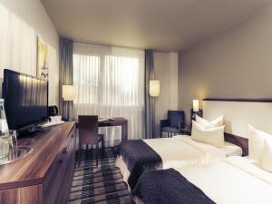 a hotel room with two beds and a desk at Sunday Hotel Saarbrücken Süd in Saarbrücken