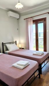 two beds in a room with a window at Theros in Makrygialos