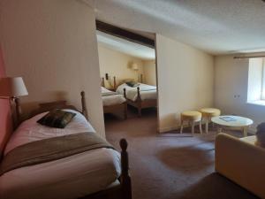 a hotel room with two beds and a table and chairs at Logis Hôtel La Fleur de Lys in Cormatin