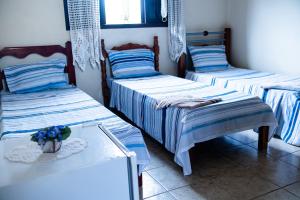 a room with three beds with blue and white stripes at Recanto the beach pousada in Iguape