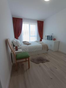 a bedroom with a bed and a chair and a window at Cazare Rasnov cu vedere spre Postavaru in Râşnov