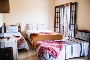 a room with two beds and a table and a window at Recanto the beach pousada in Iguape