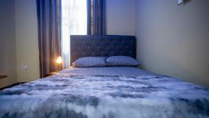 a bedroom with a bed with a blue comforter and a window at cozyairbnb in Otinshi
