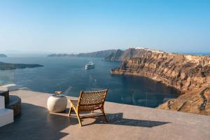 a chair sitting on a ledge with a view of the ocean at Nelya Suites in Megalochori