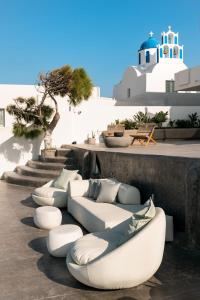 a row of white couches sitting on a patio at Nelya Suites in Megalochori +35 photos