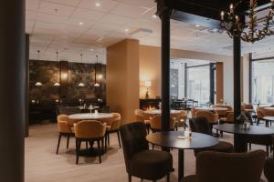 a restaurant with tables and chairs and windows at Home Hotel Baltzar in Malmö